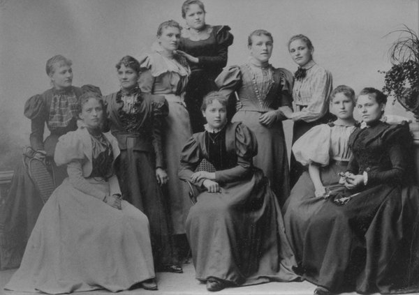 Schwarz-weiß Gruppenbild von Arbeiterinnen in Kleidern.