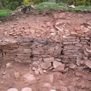 Bild eines Grabungsschnittes, in dem Reste einer Mauer zu sehen sind.