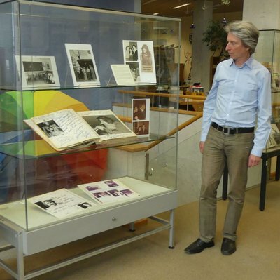 Bild von Nanu-Kurator Wolfgang Knapp in Hemd, wie er eine Ausstellungsvitrine mit mehreren Büchern betrachtet.